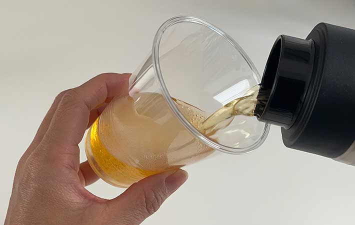 真空断熱炭酸ボトルからコップにビールを注ぐ手元