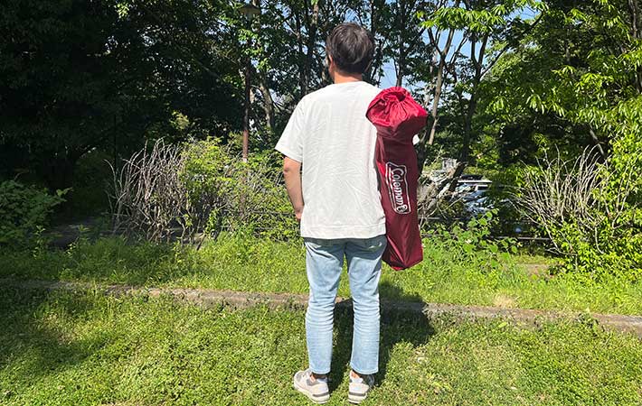 コールマン『ワンマイルチェア』を肩に掛けた男性