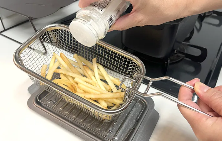 和平フレイズ『角型揚げざる』を使ってポテトに塩をふる様子